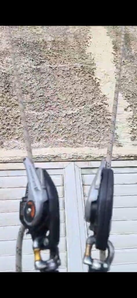 תקריב של גלגלות וציוד גלישה תלויים על חבלים מול קיר טיח משופשף