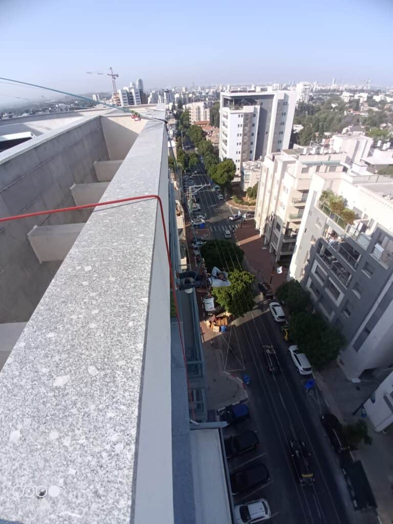 עבודות בגובה על מגדל מגורים עם נוף עירוני — סנפלינג בסיס - בסיס פתרונות בגובה