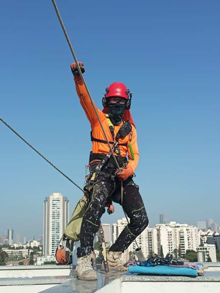 עובד גובה של בסיס עם ציוד בטיחות מלא לפי תקנות עבודה בגובה - בסיס פתרונות בגובה