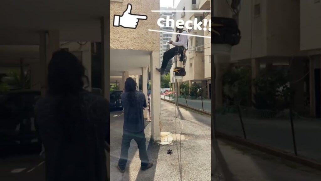 עובד בגובה על סולם, מבצע בדיקת בטיחות באתר בנייה.