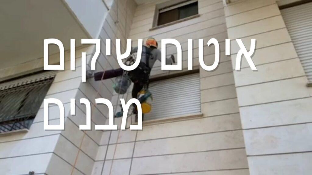 עובד בגובה עם ציוד בטיחות על קיר בניין, עבודות בגובה.