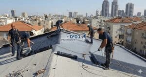 עובדי בניין מבצעים עבודות בגובה על גג בניין בעיר.