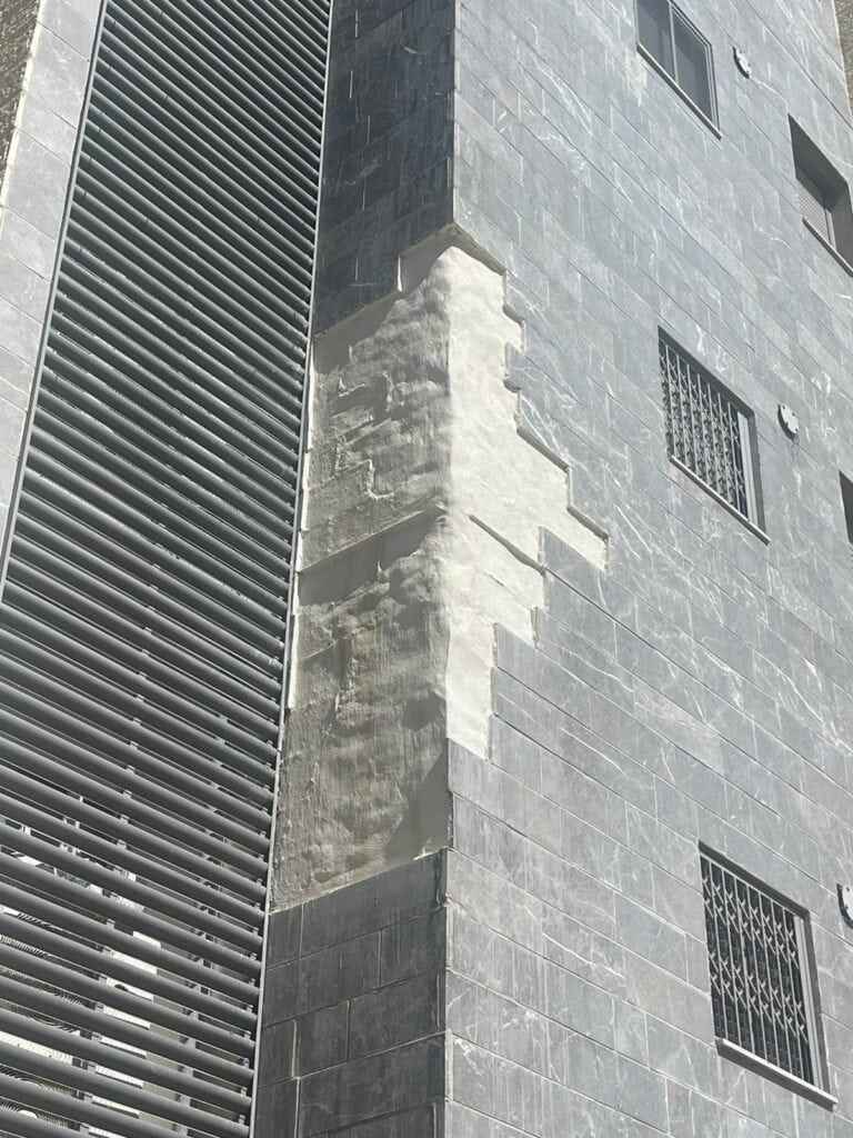 עבודות בגובה על קיר בניין עם סולם ומעקות בטיחות.