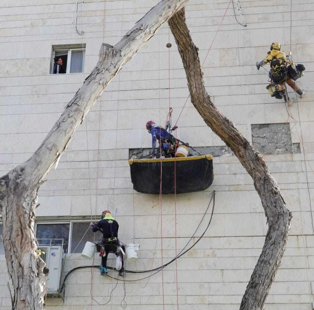 עובדי גובה עם ציוד בטיחות על בניין גבוה.