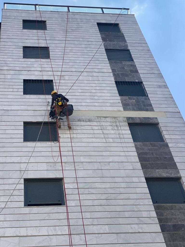 עובד בגובה עם ציוד בטיחות על בניין מודרני.